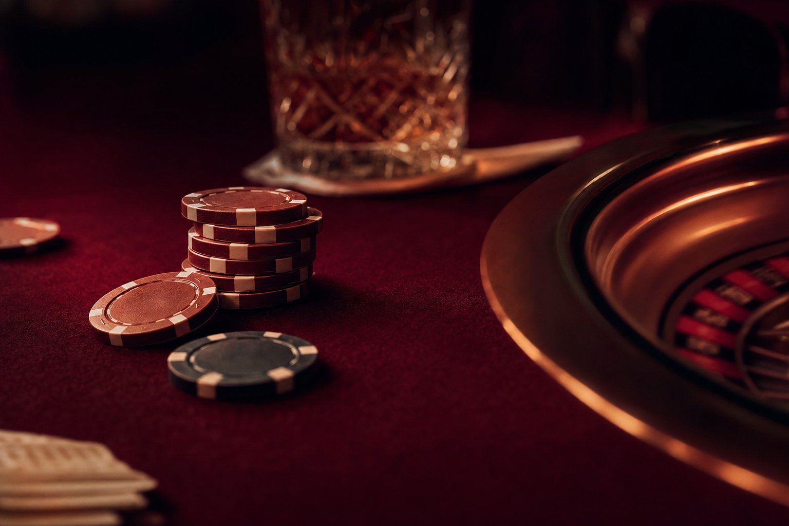 Vista sobre el tapete granate de una mesa de casino bajo luz de bronce rasante
